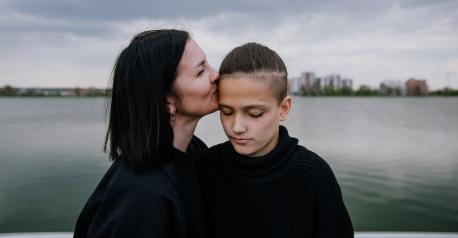 Olesia of Kyiv kisses her teenage son, Matvii, who lives with a disability. The two spent the first days of the Ukraine war hiding in a basement. 