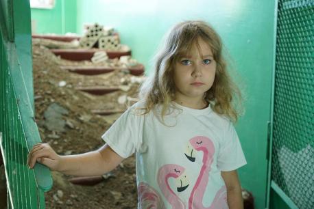 Eight-year-old Nastya stands amidst rubble in her damaged school in Buzova, Ukraine.