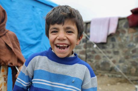 Boy smiles outside of the camp where he lives since their homes were destroyed in recent flash floods
