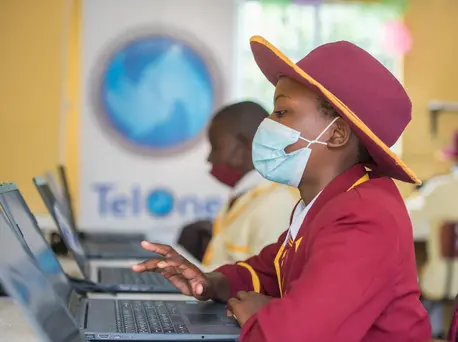 Girl in Hat and COVID Mask Using Computer