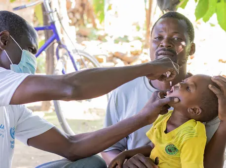 A father holds his 2-year-old son while he receives his polio vaccine in Masulama village, Karonga District, northern Malawi. A father holds his 2-year-old son while he receives his polio vaccine in Masulama village, Karonga District, northern Malawi.
