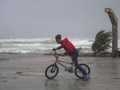 A youth rides his bike in Nagua, Dominican Republic, on Sept. 19, 2022, as Hurricane Fiona passes through the country. 