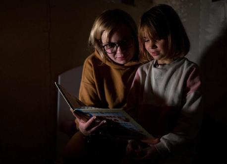 In Bucha, Ukraine, 7-year-old Varvara reads her favorite fairy tale, the story of a fox who is afraid of the spring, by candlelight. 