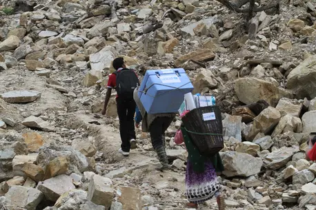 Health care workers carry UNICEF-provided vaccines on difficult terrains in Barpak Village, Nepal. Health care workers carry UNICEF-provided vaccines on difficult terrains in Barpak Village, Nepal.