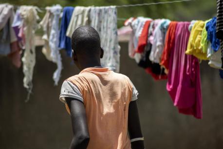 An adolescent girl looks at laundry hanging on clotheslines, her back turned to the camera