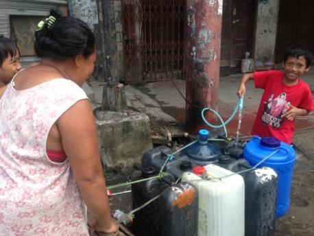 Kent Page, 2013. A family collects water at one of the 30,000 water access points across Tacloban that UNICEF and its partners restored this weekend.