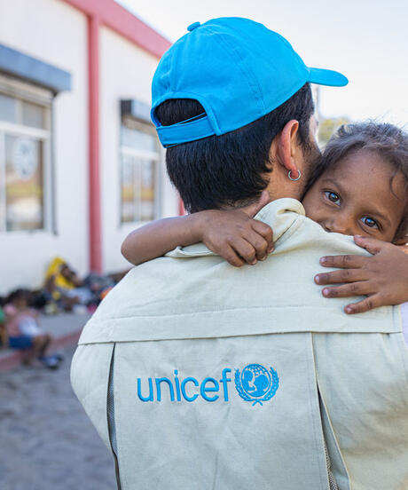 Happy girl being held by a UNICEF worker