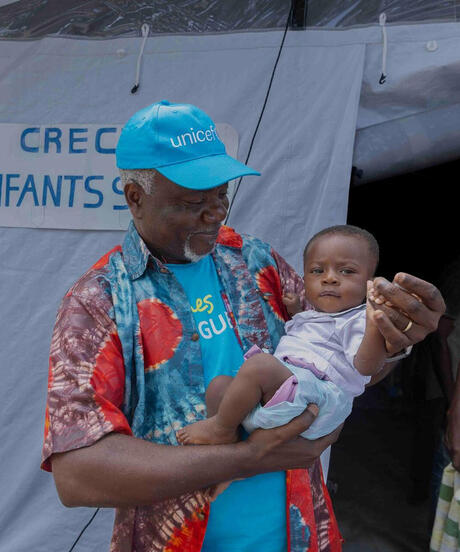 Man in UNICEF hat holding a baby