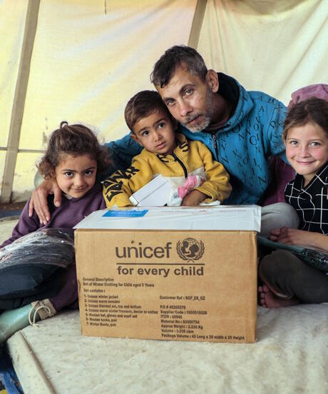 Family sitting behind a UNICEF supply box