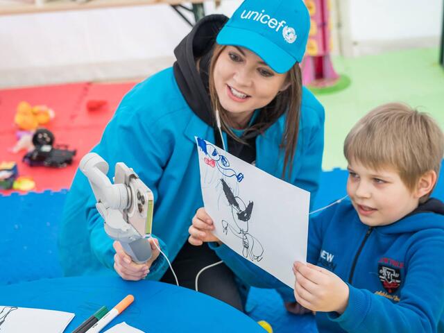 Yulia from UNCEF and Kostya, 7, are showing Kostya’s drawing of Wolverine during the live chat with Hugh Jackman who played Wolverine in X-men.