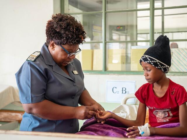 Female nurse touching young girl's finger for blood test