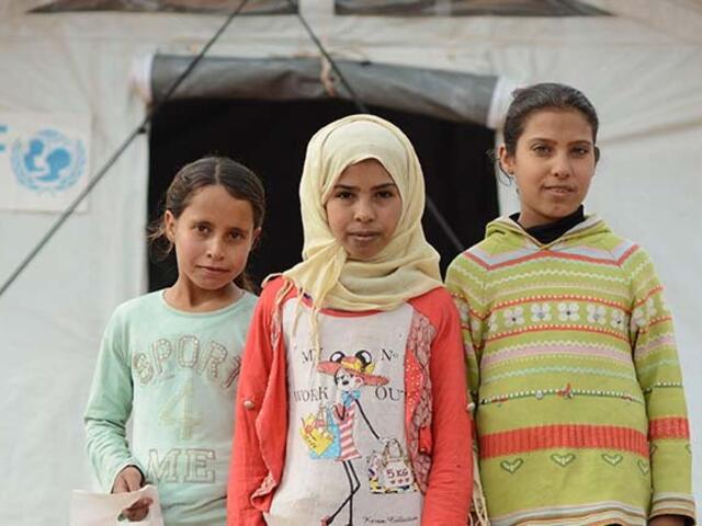 Three children standing in front of a UNICEF tent