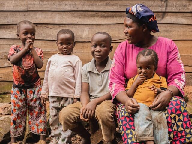 In South Kivu province, DRC, a mother sits with her four children outside her drink stall, a business she started with cash assistance from UNICEF that is helping the family survive.