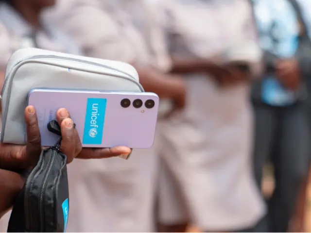 Woman's hand holds smartphone with UNICEF logo on the back of the device