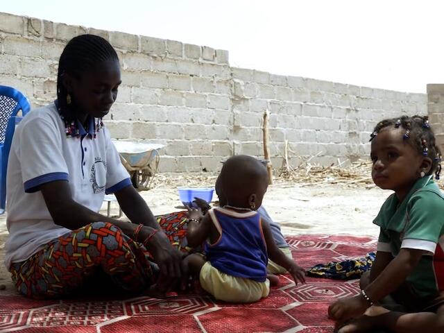 Displaced by violence, a mother and her children sit outside in Burkina Faso. 