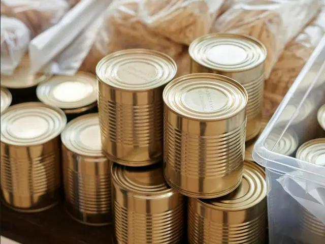 A pile of unmarked cans, in front of stacks of plastic-wrapped foods