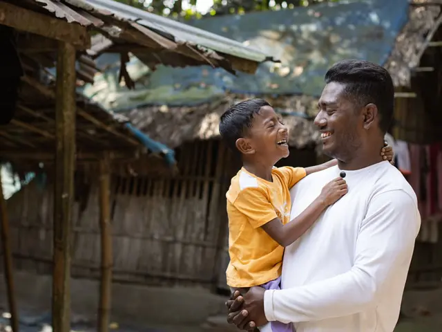 Father holding a young boy while both laugh