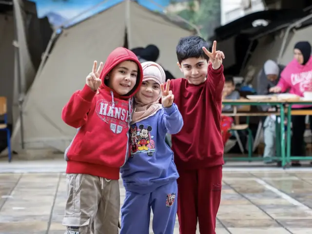 A group of children stand in front of a tent in a UNICEF-supported displacement site in Lebanon in 2026.