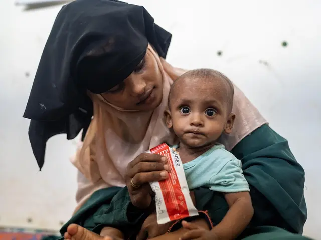 A Rohingya refugee mother feeds her child ready-to-use therapeutic food supplied by UNICEF to treat severe malnutrition.