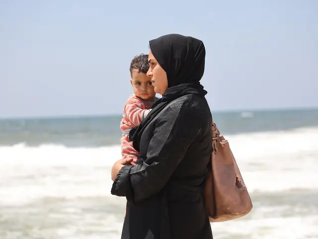 A Palestinian mother holds her baby near the Mediterranean Sea. 