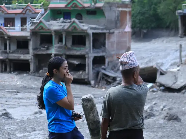 On Aug. 27, 2026, a UNICEF staffer talks to a community member in  Nuwakot District, Bagmati Province, Nepal, as homes and surrounding areas can be seen covered in mud. 