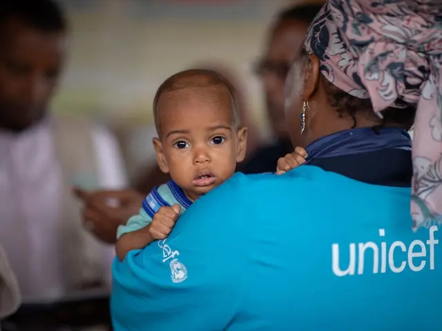 A UNICEF staff member holds a baby during a visit to the UNICEF-supported health and nutrition facility in Moqor iyo Mayow IDP settlement in Somalia on Aug. 5, 2026.