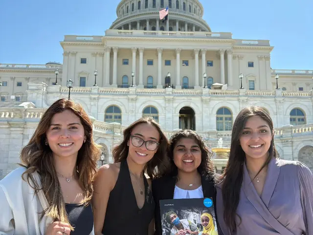 Four women standing in front of the Capitol building holding UNICEF materials