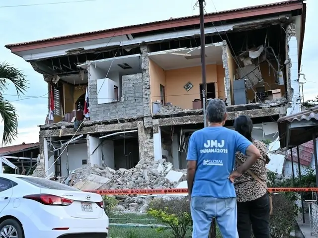Man and woman look up at earthquake damaged home in Panama
