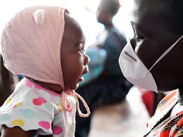 Man with Mask Holding Baby