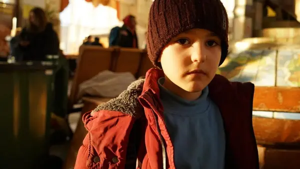 7-year-old Maksym wears a red winter coat and dark red cap.