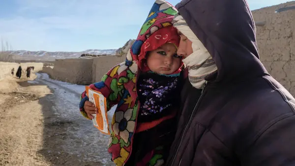 A father holds his daughter after she has received a checkup at a health center in Afghanistan.