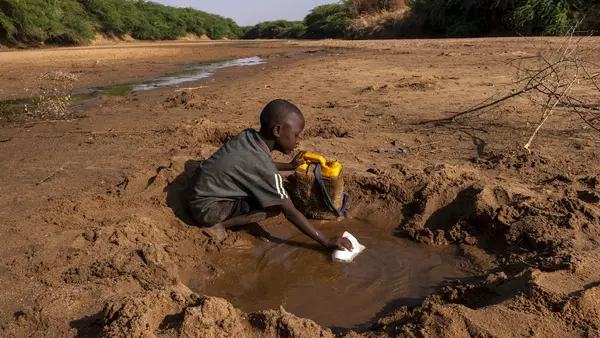 A young boy collects what little water he can from a dried up riverbed in Dollow Somalia, where severe drought has taken hold..