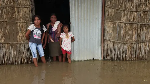 A woman and children stand in floodwaters in Primavera, a rural community located in Cura Mori District outside the city of Piura, Peru.