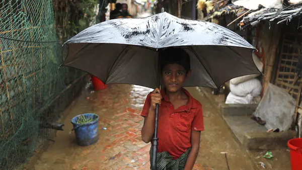 In Cox's Bazar, Bangladesh, a boy stands under an umbrella to protect himself from heavy rains caused by Cyclone Mocha on May 14, 2023.