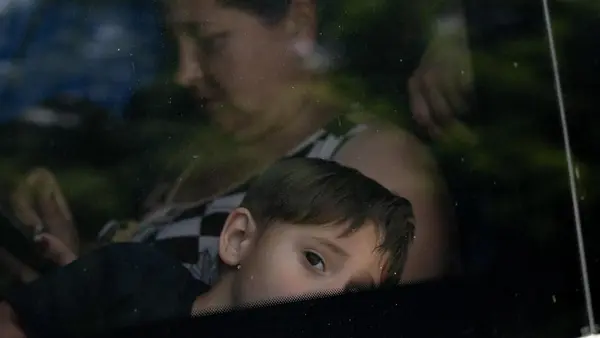 A child and parent evacuating by bus from Kherson, Ukraine, following the dam collapse on June 6, 2023.