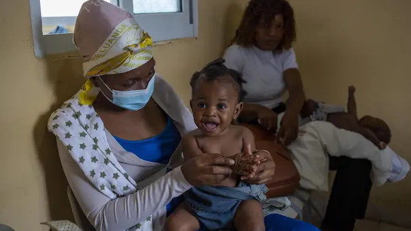 Nine-month-old Lwisani is held by her mother prior to receiving a dose of measles and rubella vaccine at Catambor Health Centre in Luanda, Angola