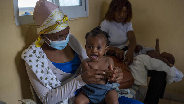 Nine-month-old Lwisani is held by her mother prior to receiving a dose of measles and rubella vaccine at Catambor Health Centre in Luanda, Angola