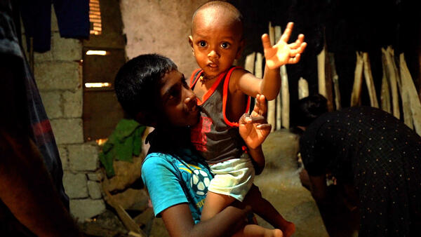 Ariesh, 10, holds his brother Aswin, almost 2, inside their home in rural Sri Lanka.