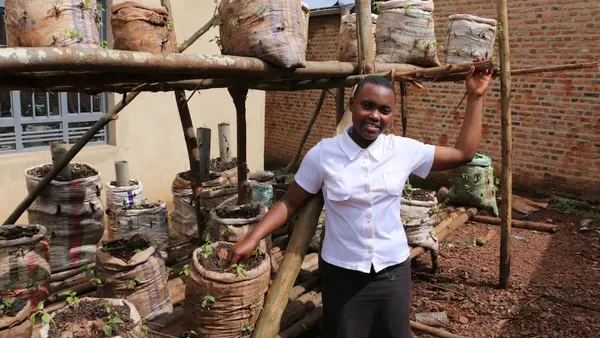 In Burundi, Sandrine, 16, stands with vegetables grown in bags of dirt, part of the Creatables project funded by UNICEF Australia. 