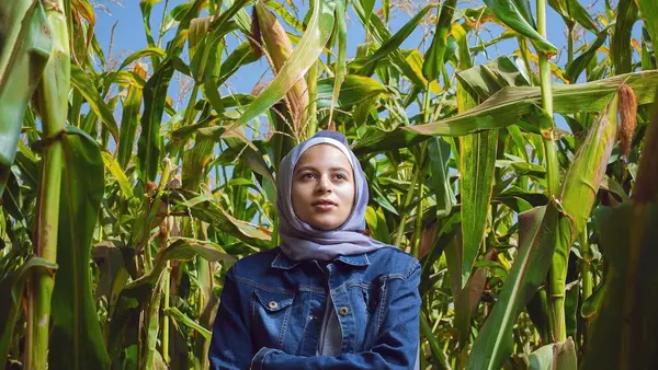 A young woman stands in the middle of a corn field in Egypt.