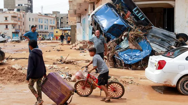 A boy pulls a suitcase past debris in a flash-flood damaged area in Derna, eastern Libya, on September 11, 2023. 
