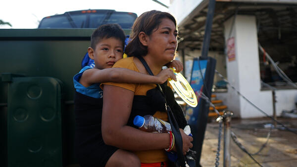 A mother carries her child on her back to make her way through an area of Guerrero state, southwestern Mexico, in wake of Hurricane Otis. Photo by Getty Images.