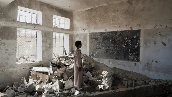 A student stands in the ruins of one of his former classrooms at the Aal Okab school in Saada, Saada Governorate, Yemen.