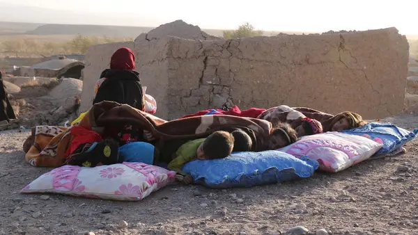 Afghan children rest under a blanket beside damaged houses after earthquake in Sarbuland village of Zendeh Jan district of Herat province on Oct. 7, 2023.