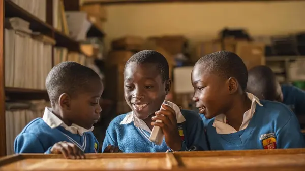Partially blind students at UNICEF-supported St. Bernadette Primary School in Hoima, Uganda, listen to a recorded lesson from a Victor reader.