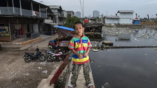 Satrio, 7, stands on a sea wall near his home in the Muara Baru neighborhood of North Jakarta, Indonesia.