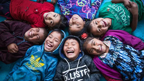 Seven schoolchildren, members of the indigenous community of Chicoy of Todos Santos Cuchumatánin, who live in the province of Huehuetenango, Guatemala, laugh and smile together on the floor of their classroom on the last day of school.