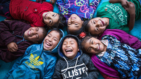 Seven schoolchildren, members of the indigenous community of Chicoy of Todos Santos Cuchumatánin, who live in the province of Huehuetenango, Guatemala, laugh and smile together on the floor of their classroom on the last day of school.