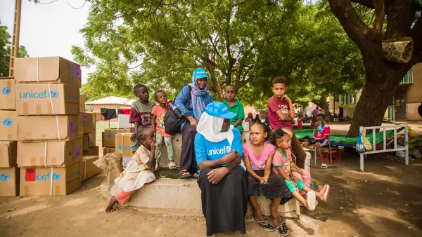 UNICEF staff engage with displaced children at a gathering point in Madani.