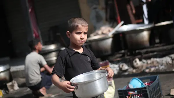Abdul, 8, in Rafah city, Gaza, heads to a food distribution point with an empty bowl he hopes to fill so that his mother and father and three brothers can eat.